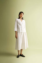 White front twist top, by Nicobar, styled with a midi skirt and black loafers.