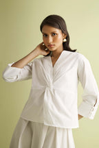 White front twist top by a nameless vendor, with long sleeves and cuff button detail.